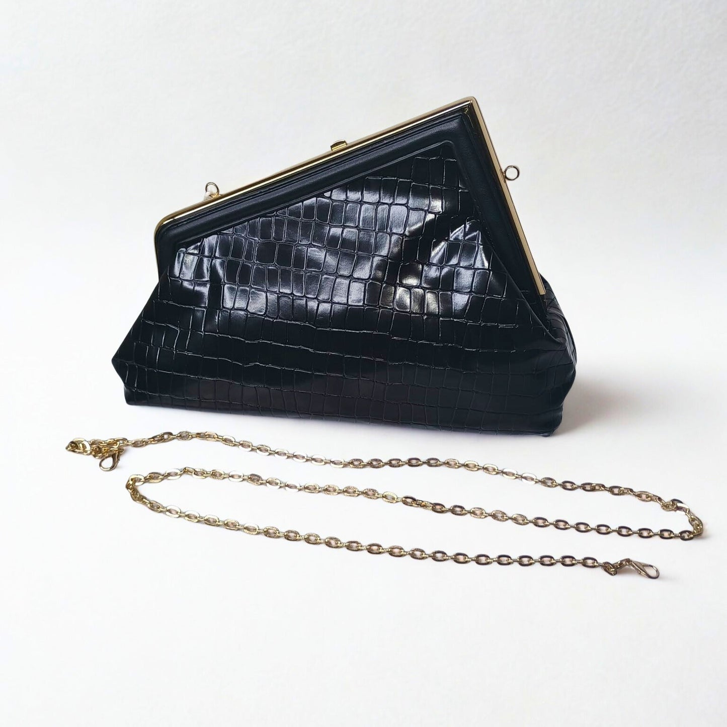 Black crocodile skin handbag with gold chain on a white background