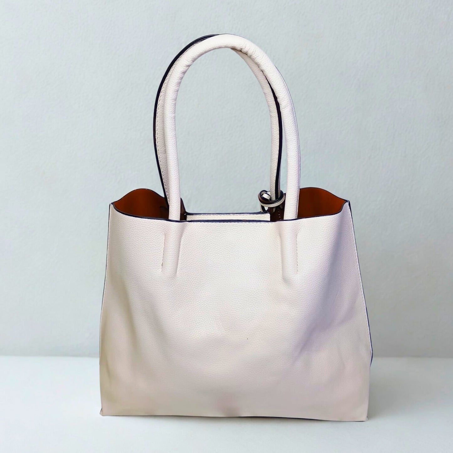 Beige handbag with brown interior on a light gray background