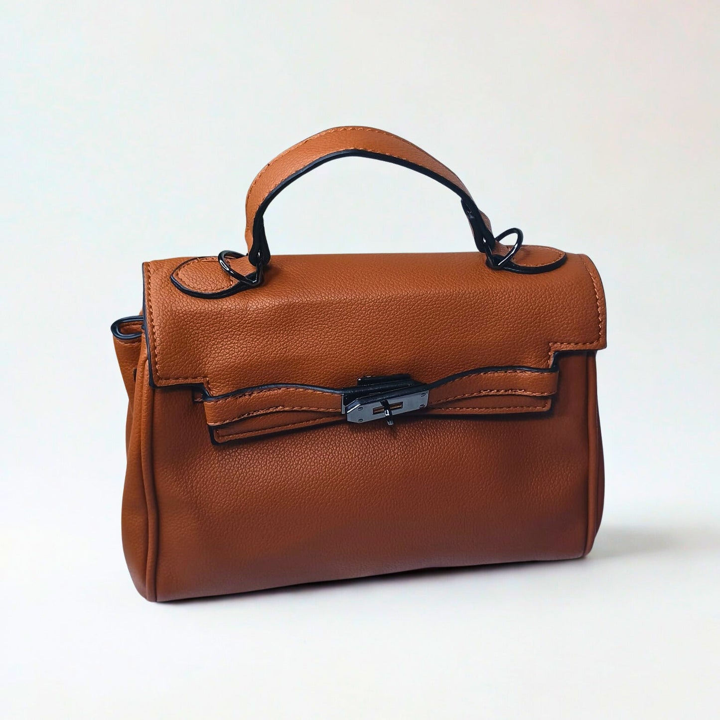 Brown leather handbag with a black handle and clasp on a white background