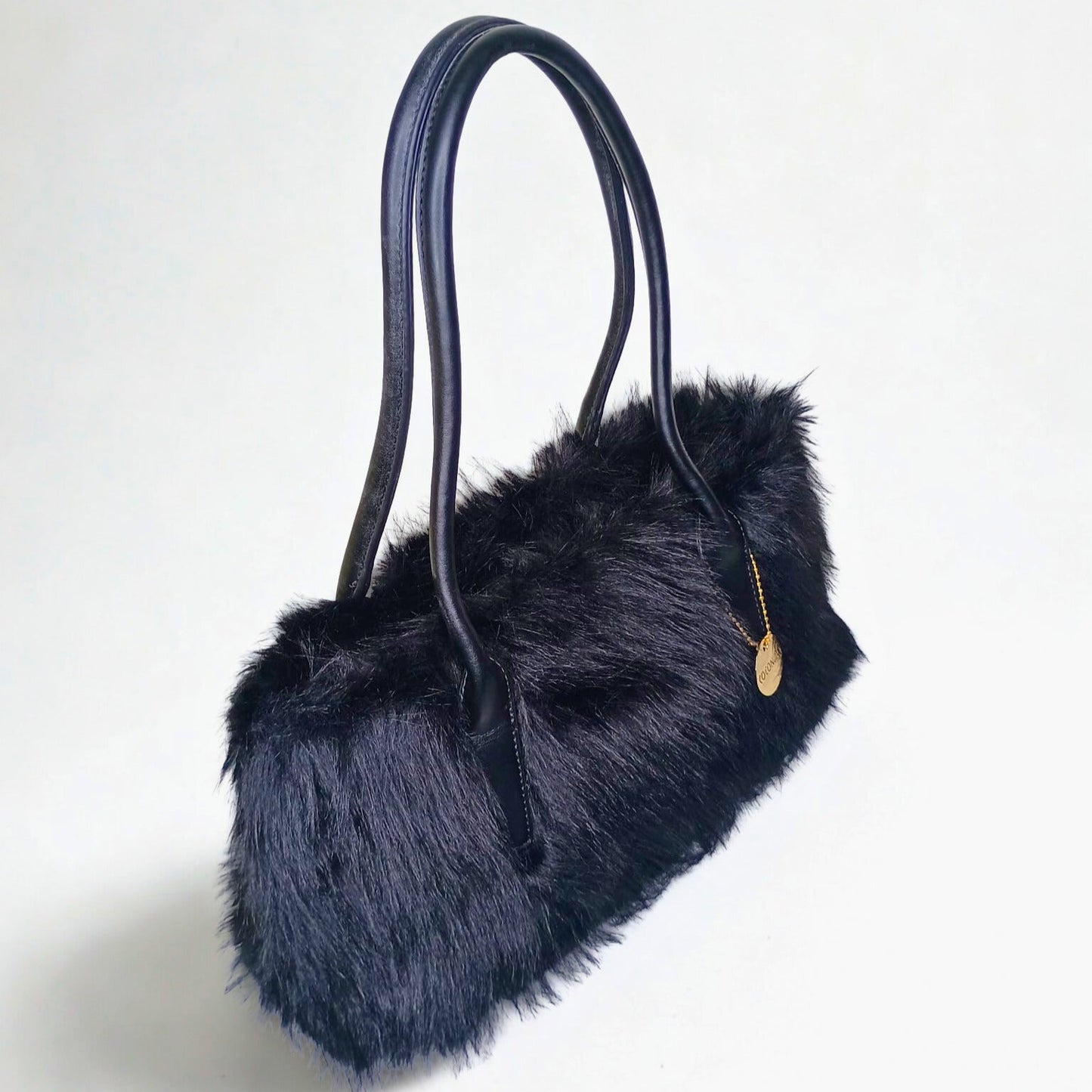 Black fur handbag with a gold tag on a white background