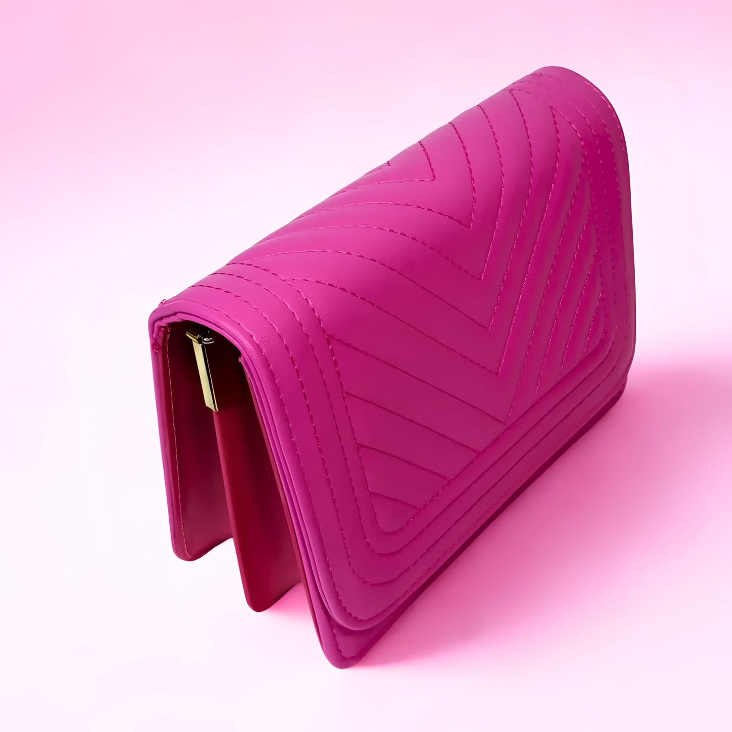 Pink quilted handbag with a gold clasp on a pink background