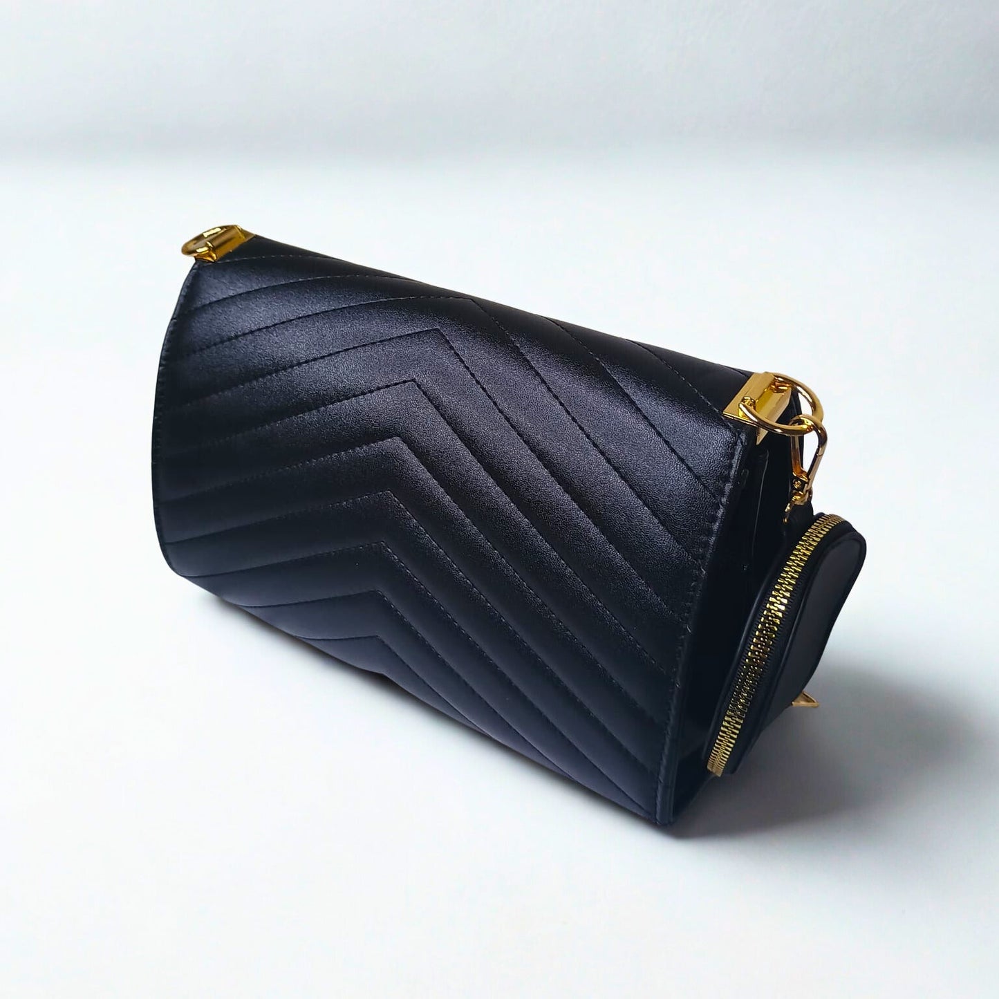 Black chevron-patterned clutch bag with gold accents on a white background