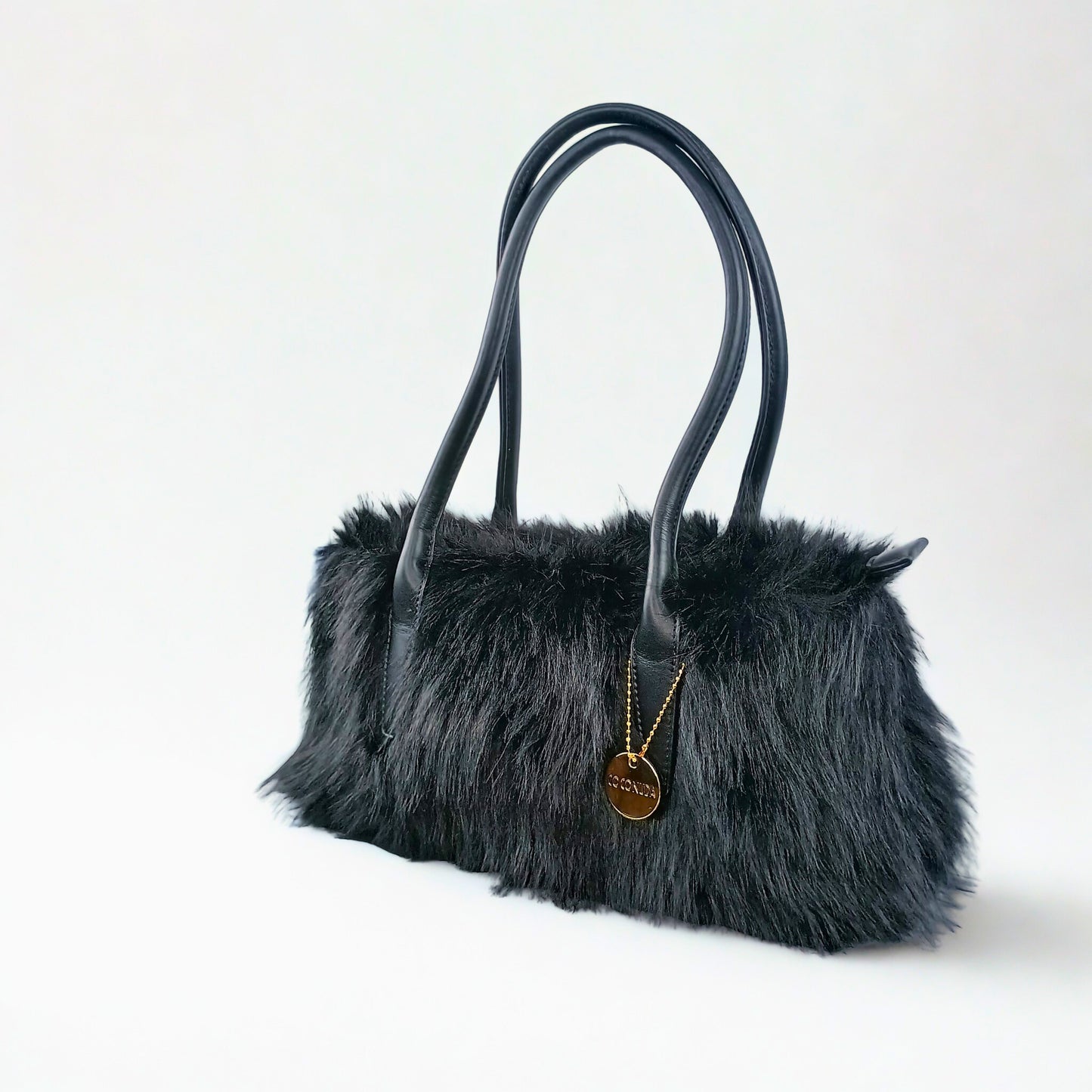 Black fur handbag with leather handles on a white background