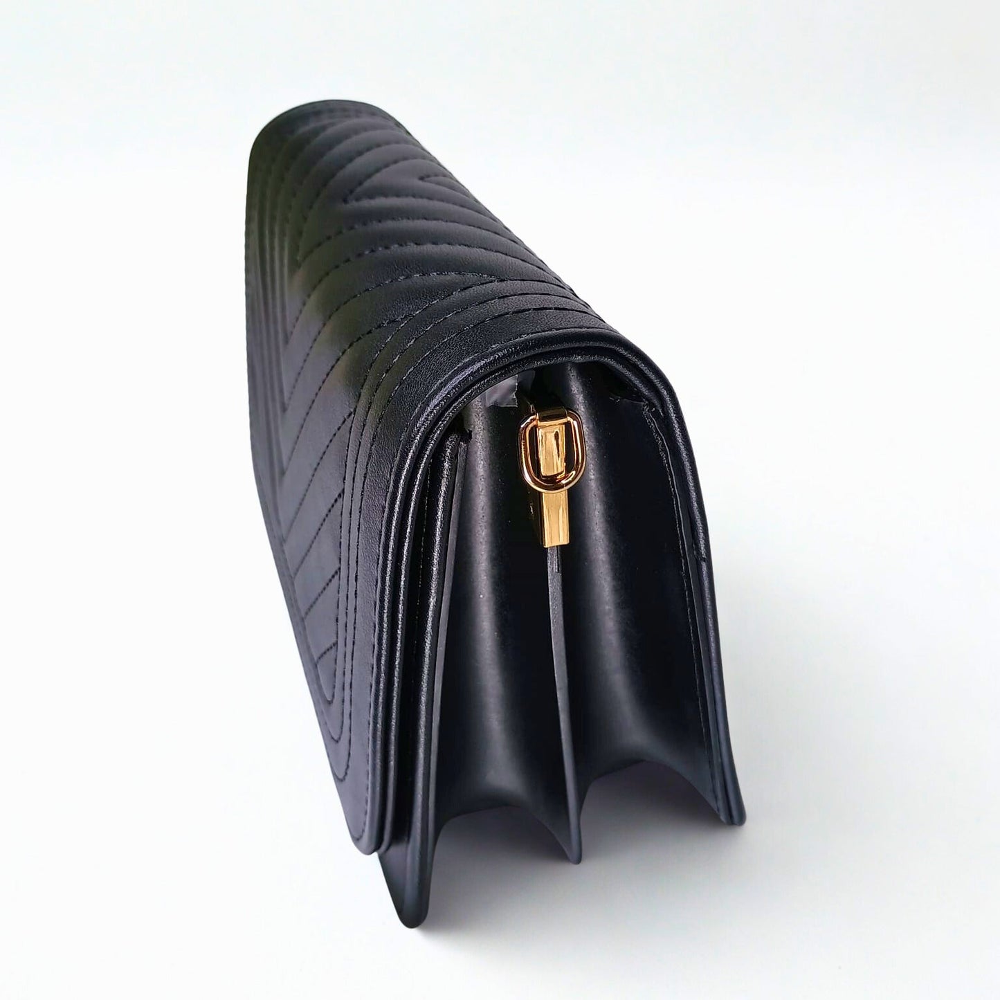 Black quilted handbag with gold clasp on a white background