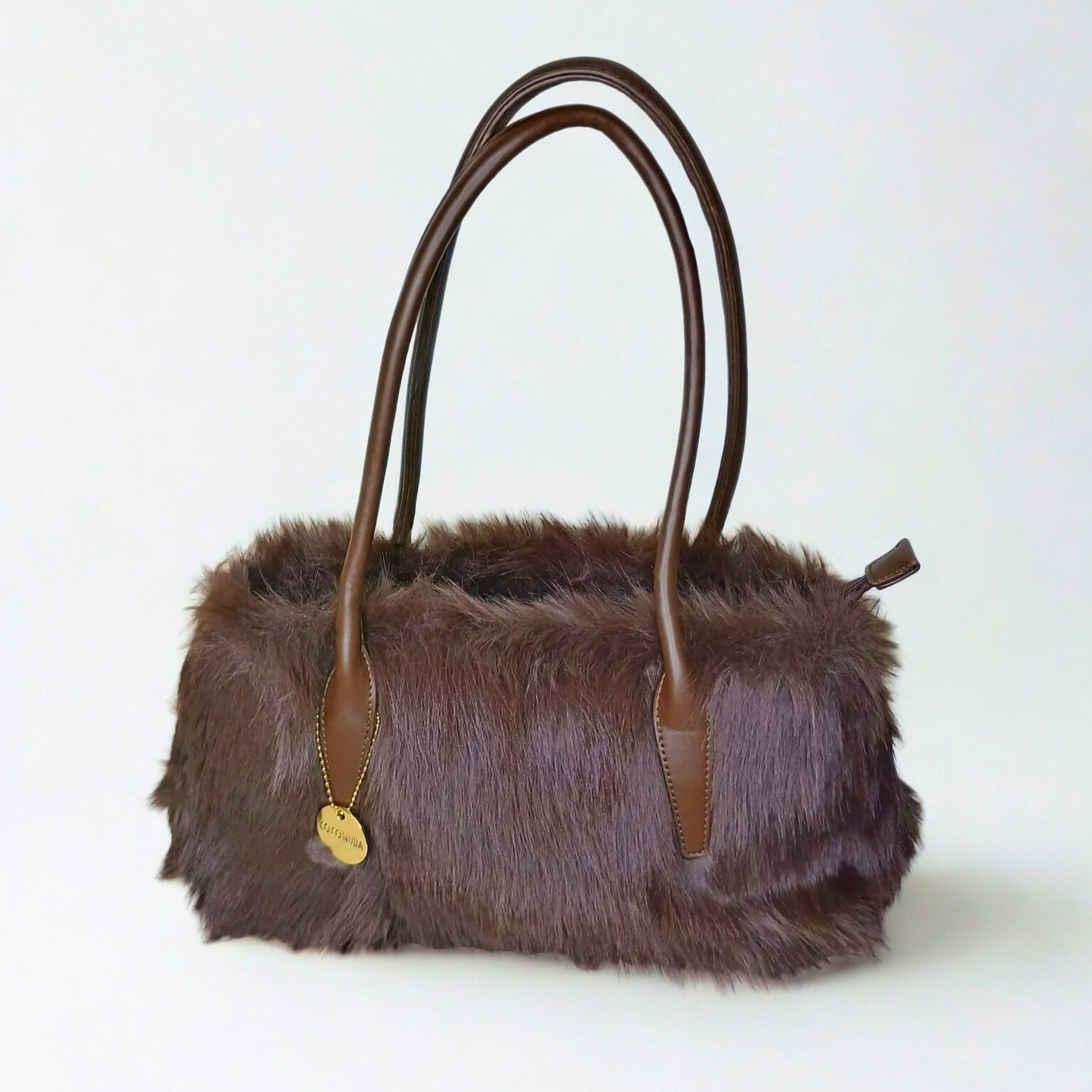 Brown fur handbag with leather handles on a white background