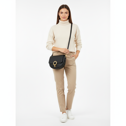 Woman wearing a beige sweater and pants with a black handbag on a white background