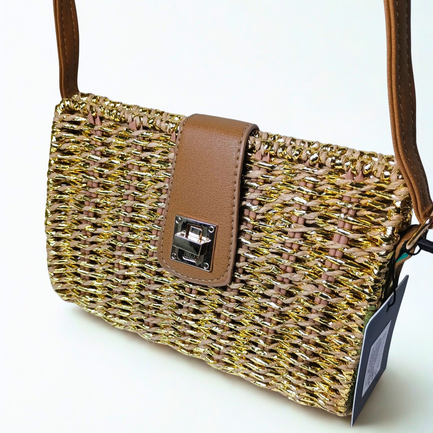 Woven handbag with brown leather strap and tag on a white background
