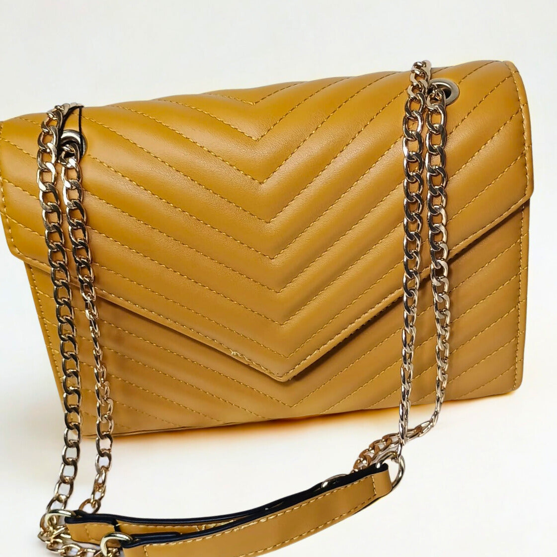 Yellow quilted handbag with a chain strap on a white background