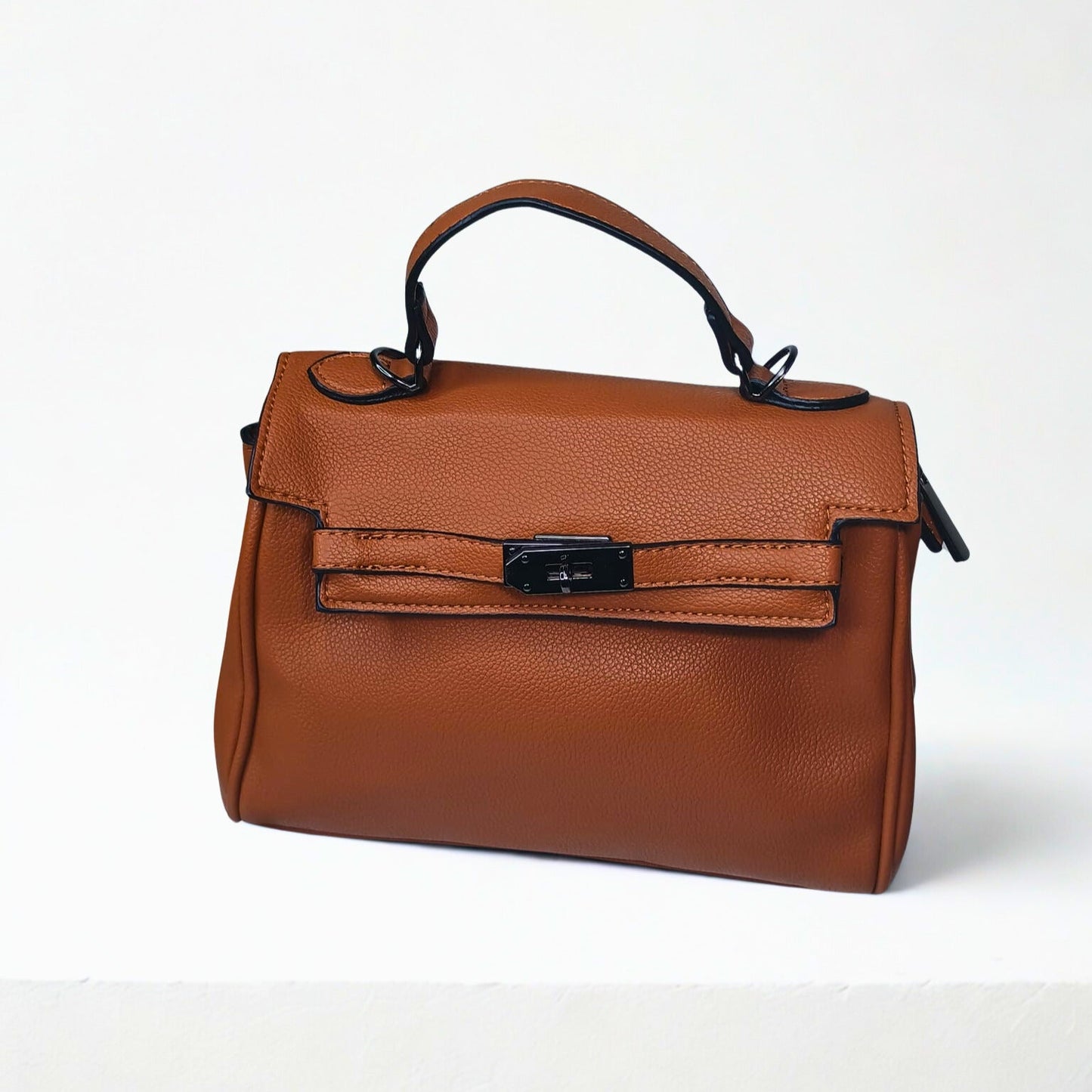 Brown leather handbag with a black clasp on a white background