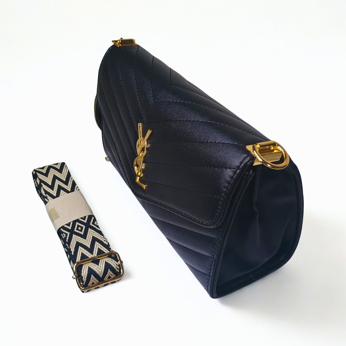 Navy blue handbag with gold hardware and a strap on a white background