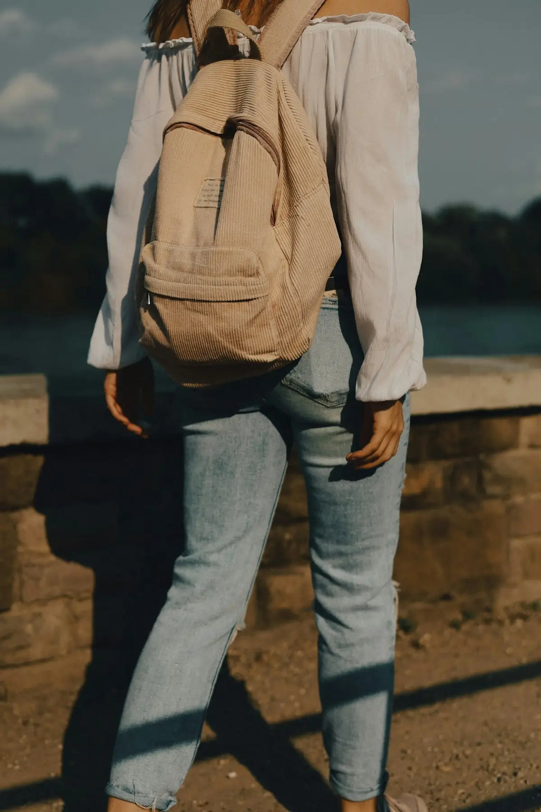 a woman with a backpack standing on a bridge