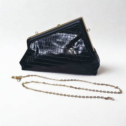 Black crocodile skin handbag with gold chain on a white background