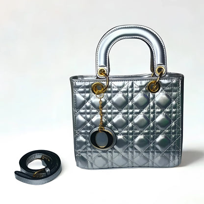 Silver quilted handbag with gold hardware and a matching keychain on a white background