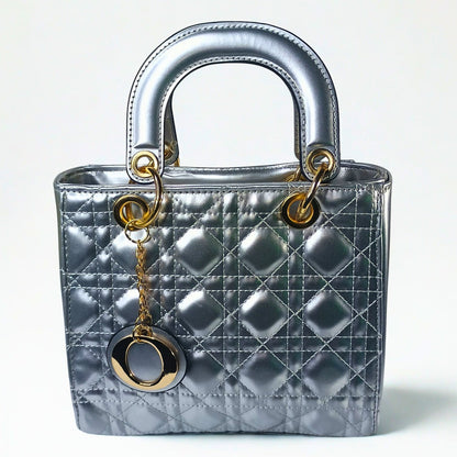 Silver quilted handbag with gold hardware on a white background