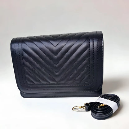Black quilted handbag with a matching strap on a light gray background