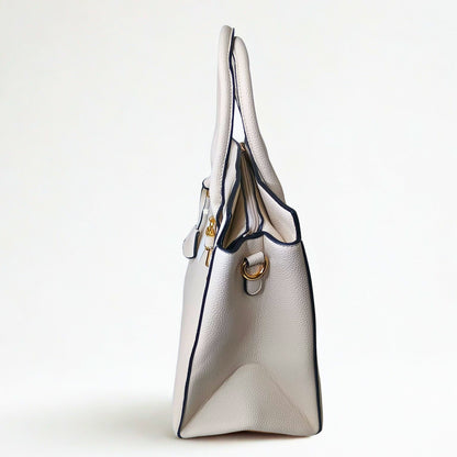 White handbag with gold accents on a light gray background