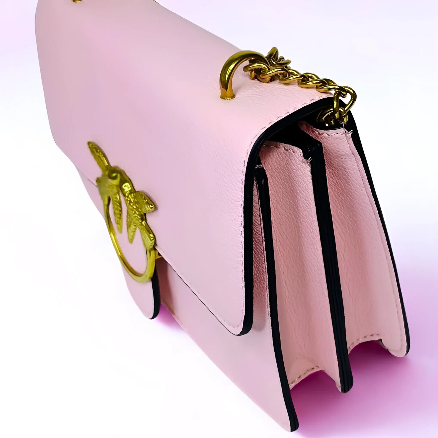 Pink handbag with gold chain handle on a light pink background