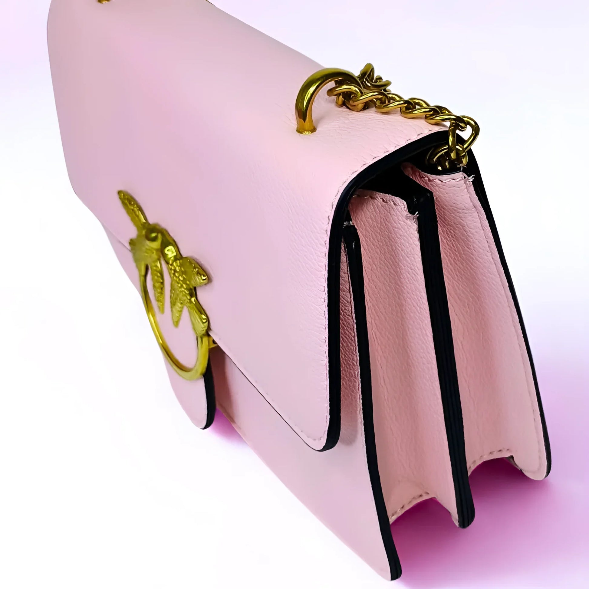Pink handbag with gold chain handle on a light pink background