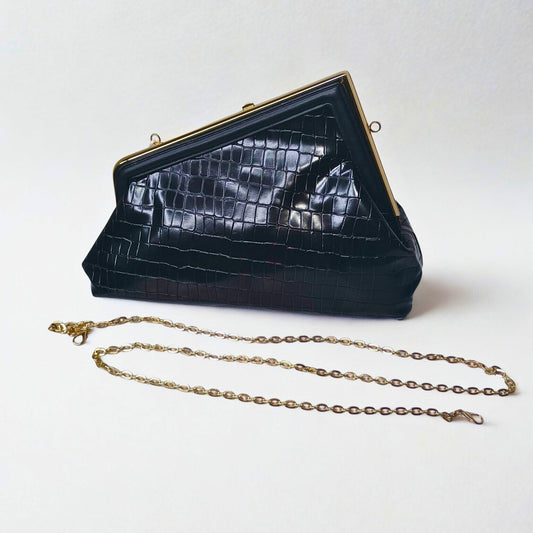 Black crocodile-patterned handbag with gold chain on a white background