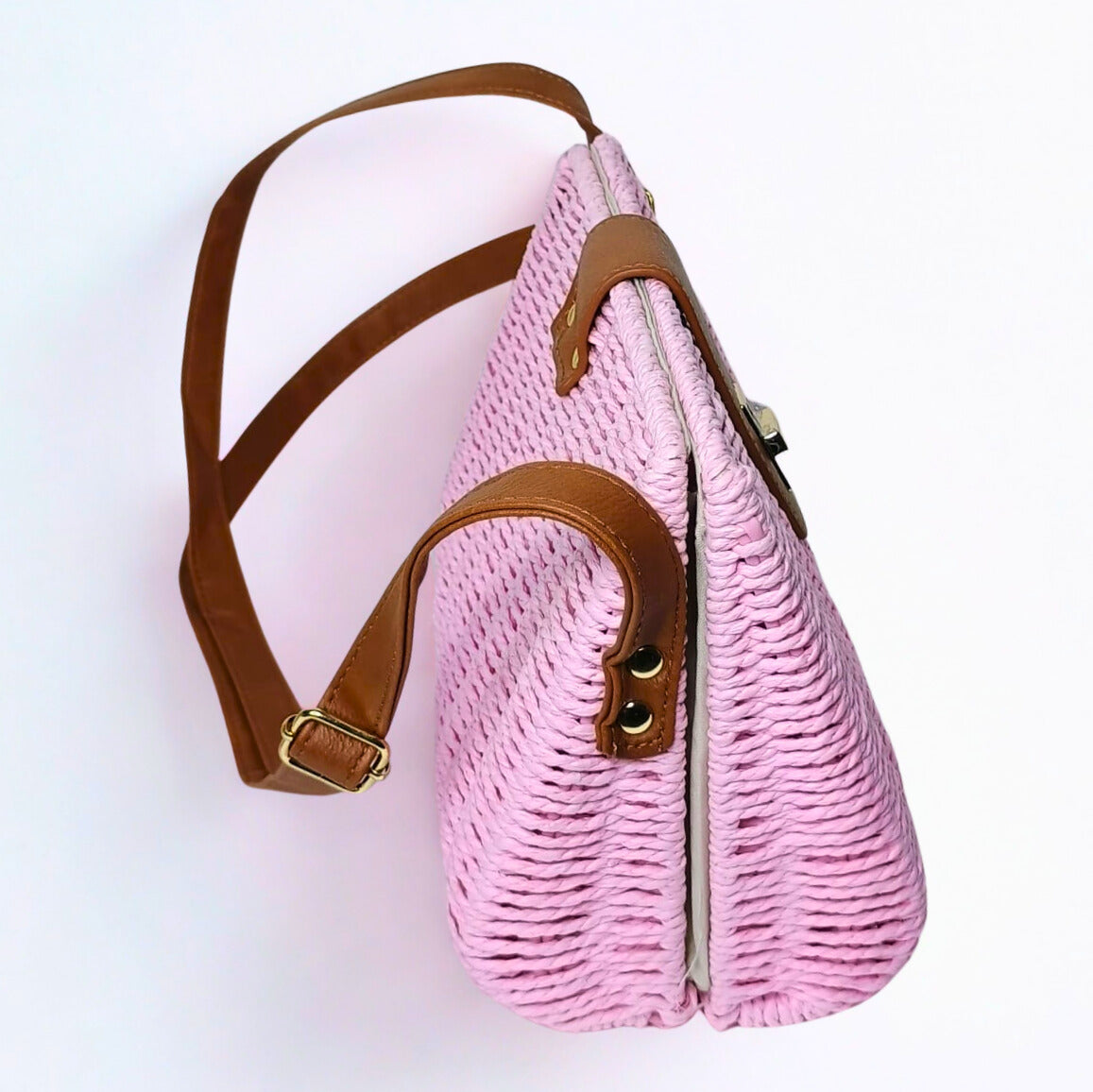 Pink woven handbag with brown straps on a white background