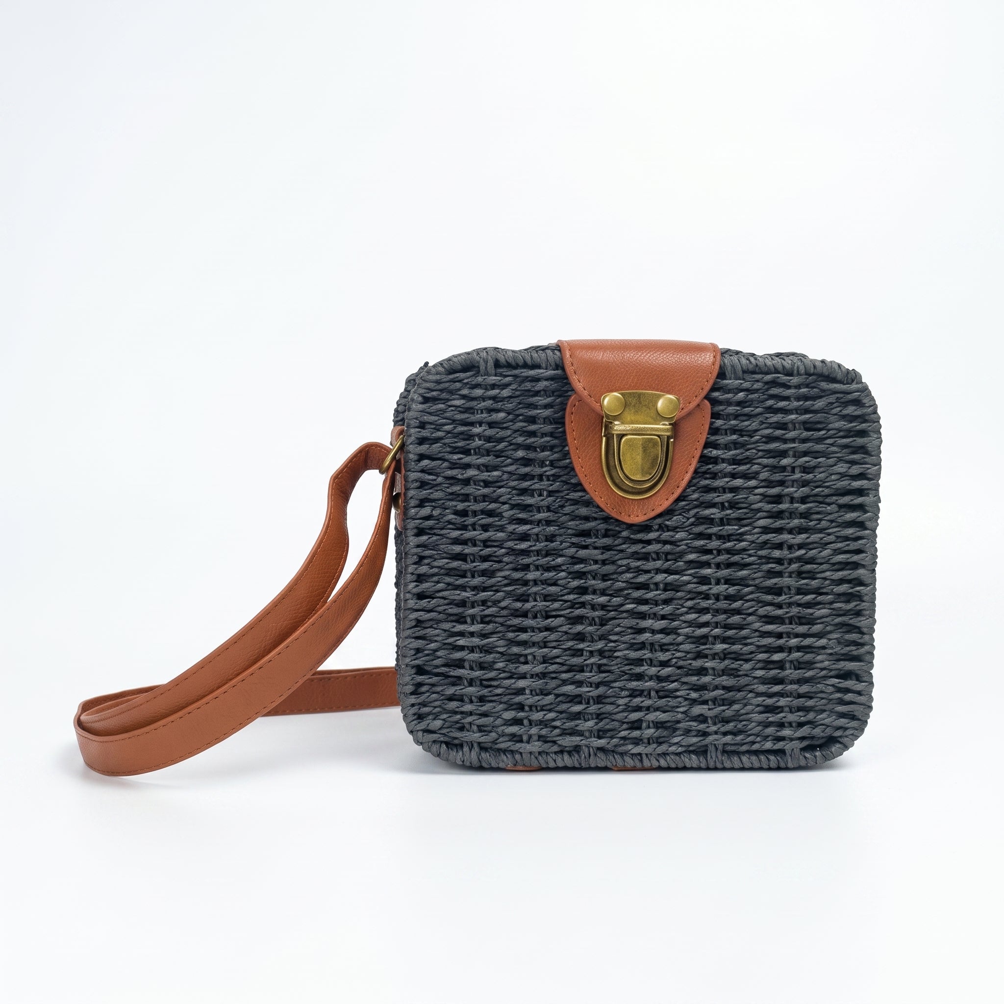 Woven handbag with brown strap and leather buckle on a white background