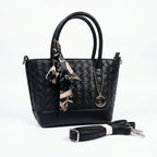 Black woven handbag with a matching scarf and detachable strap on a white background