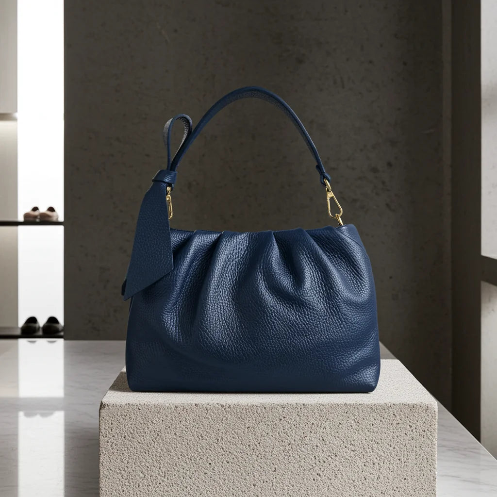 Blue handbag on a stone block with a neutral background