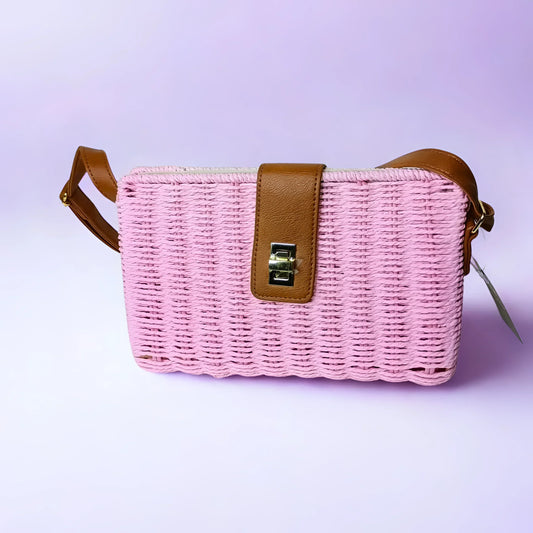 Pink woven handbag with brown leather straps on a light purple background