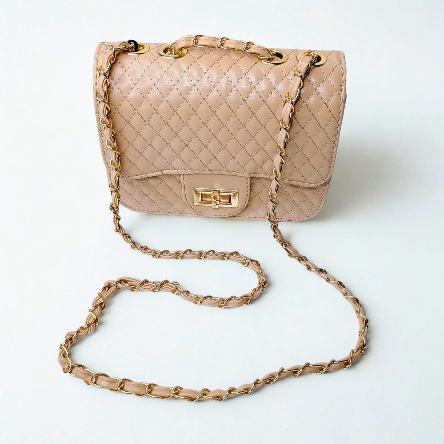 Quilted beige handbag with gold chain strap on a white background
