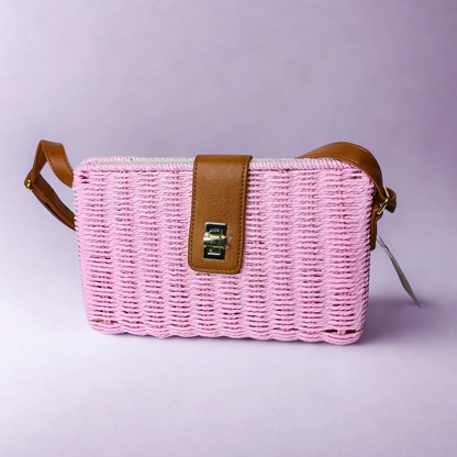 Pink woven handbag with brown leather strap on a light purple background
