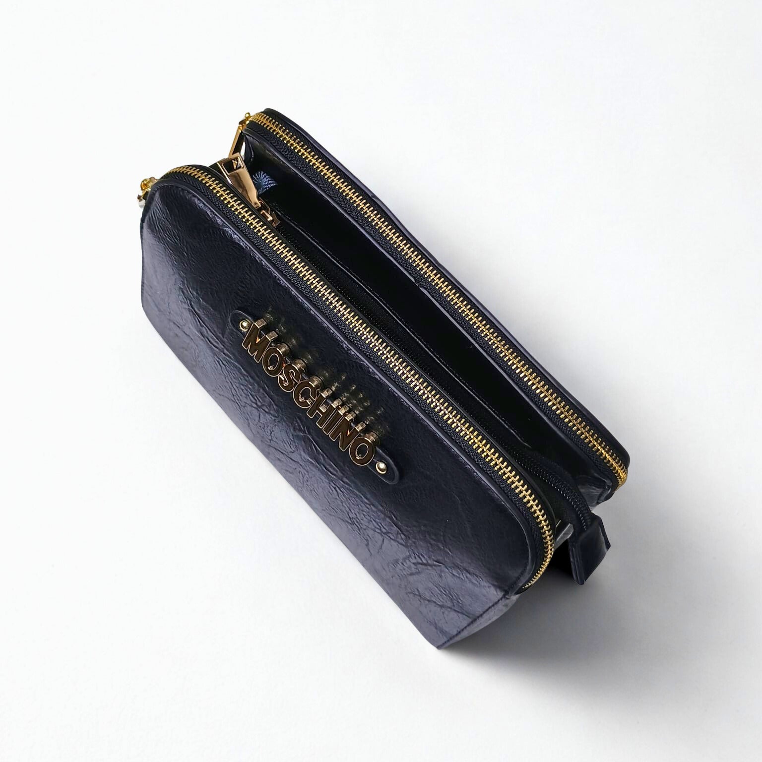 Black handbag with gold zipper and Moschino logo on a white background