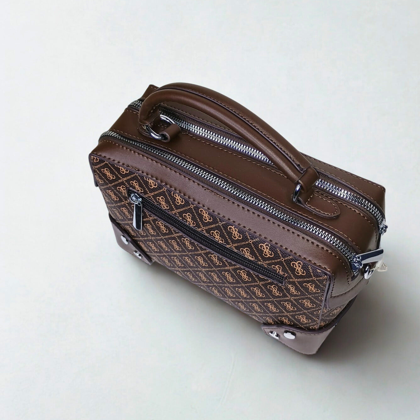 Brown patterned suitcase with zippers on a white background