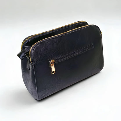 Black leather handbag with gold zipper on a white background