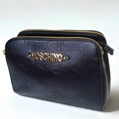 Black leather clutch bag with gold zipper and Moschino logo on a white background