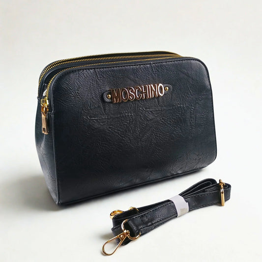 Black handbag with gold accents and Moschino logo on a light gray background