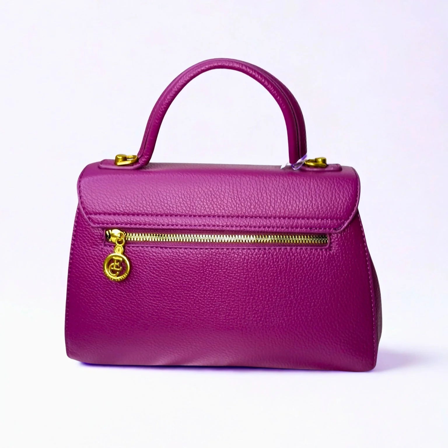 Purple handbag with gold zipper and handle on a light purple background